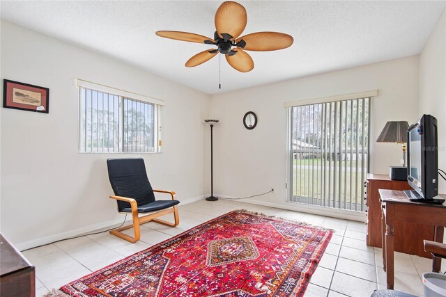 sitting room with a textured ceiling, light tile patterned flooring, a wealth of natural light, and a ceiling fan