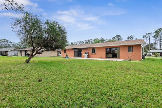 rear view of property with central AC unit, a lawn, a patio area, and stucco siding