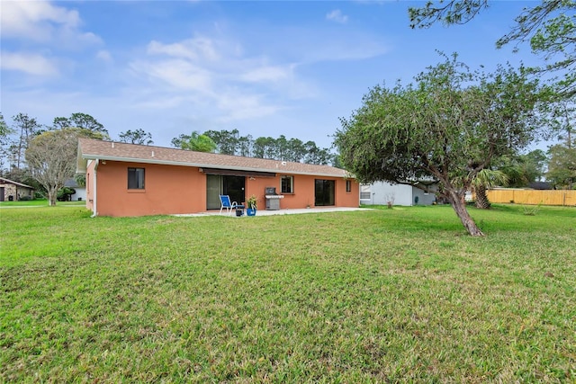 back of property featuring a patio area, a yard, fence, and stucco siding