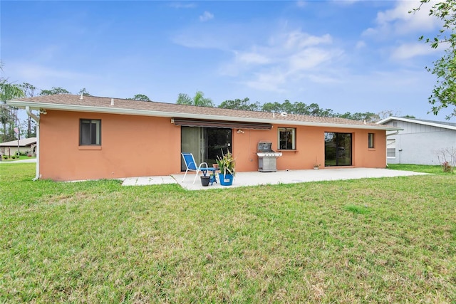 rear view of property featuring a patio area, a yard, and stucco siding