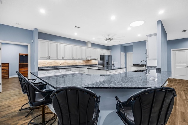 kitchen featuring white cabinetry, dark hardwood / wood-style flooring, decorative backsplash, kitchen peninsula, and high end fridge