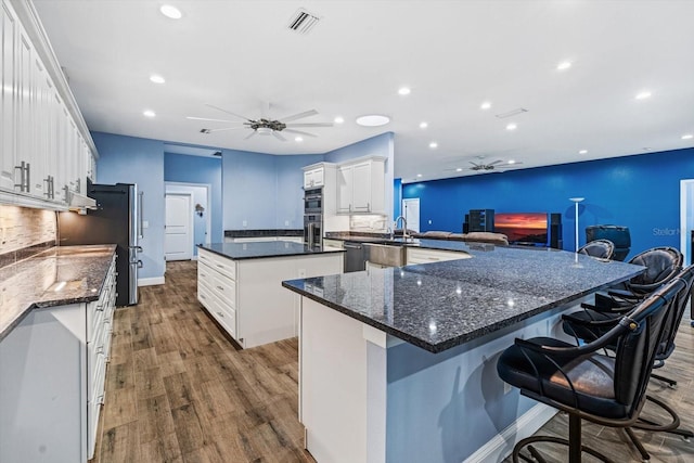 kitchen featuring ceiling fan, wood-type flooring, white cabinets, decorative backsplash, and kitchen peninsula