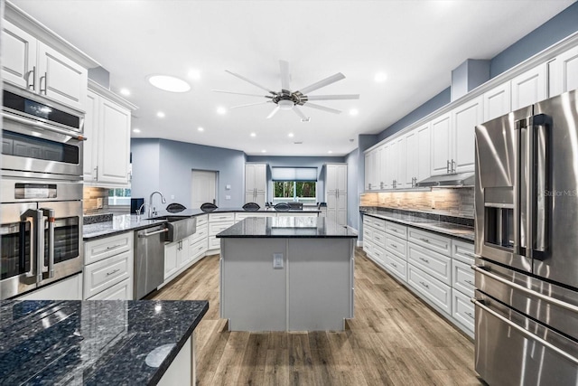 kitchen featuring white cabinetry, sink, backsplash, kitchen peninsula, and stainless steel appliances