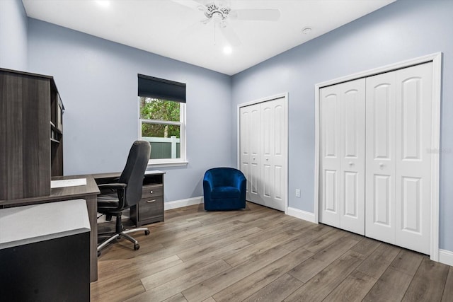 home office with light hardwood / wood-style floors and ceiling fan