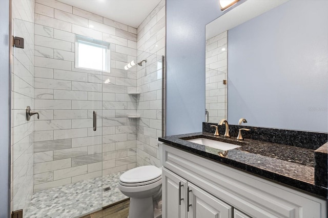 bathroom with wood-type flooring, toilet, a shower with shower door, and vanity