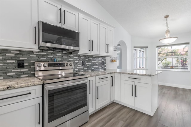 kitchen featuring lofted ceiling, white cabinetry, stainless steel appliances, decorative backsplash, and kitchen peninsula