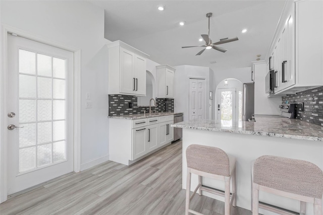 kitchen featuring white cabinetry, range, light stone counters, and kitchen peninsula