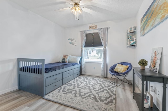 bedroom with ceiling fan, light hardwood / wood-style floors, and a textured ceiling