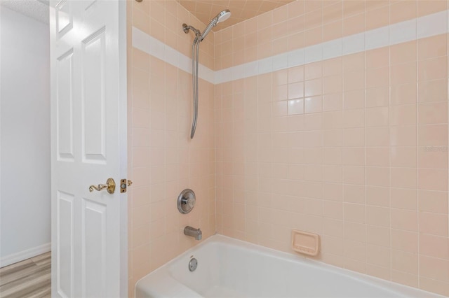 bathroom with tiled shower / bath combo, hardwood / wood-style floors, and a textured ceiling