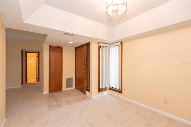 empty room with a tray ceiling and light colored carpet