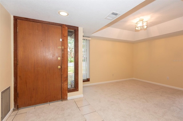 foyer with a raised ceiling and light tile patterned flooring