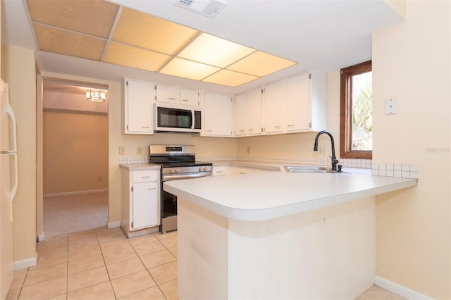 kitchen with sink, white cabinetry, light tile patterned floors, kitchen peninsula, and white appliances