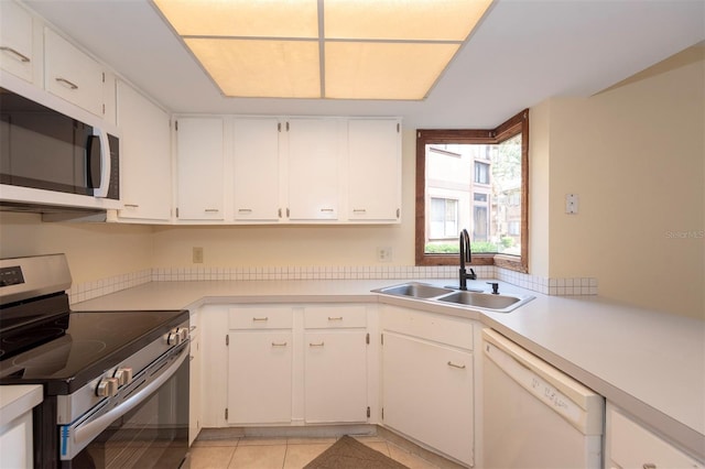 kitchen with white appliances, light tile patterned floors, sink, and white cabinets