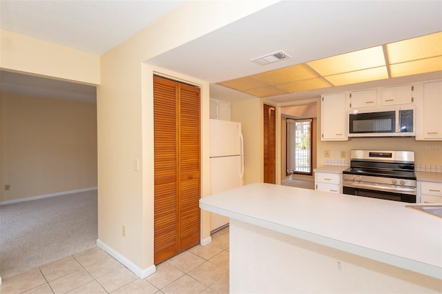 kitchen with appliances with stainless steel finishes, light carpet, and white cabinets