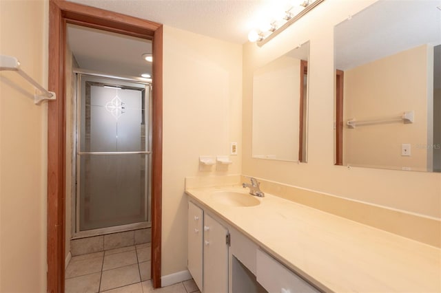 bathroom featuring a shower with door, vanity, tile patterned floors, and a textured ceiling