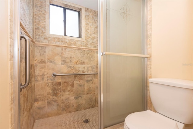 bathroom featuring toilet and a shower with shower door