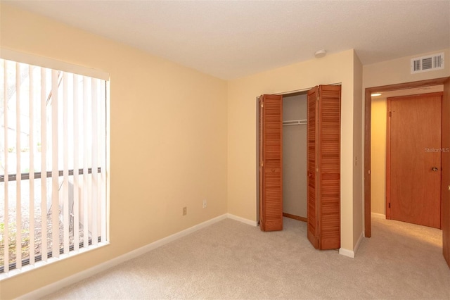 unfurnished bedroom with light carpet and a closet