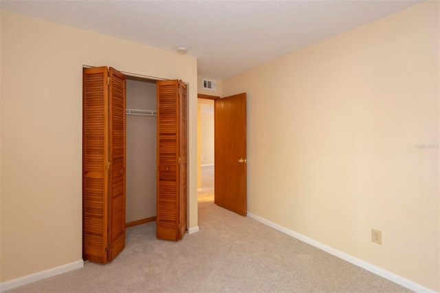 unfurnished bedroom with light carpet and a closet