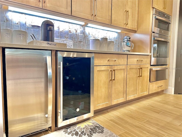 kitchen featuring beverage cooler, double oven, and light hardwood / wood-style floors