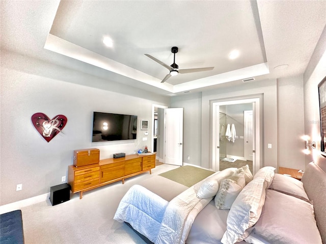 carpeted bedroom featuring ensuite bathroom, a walk in closet, a tray ceiling, a closet, and ceiling fan