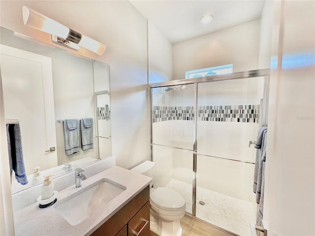 bathroom with toilet, vanity, and a shower with shower door