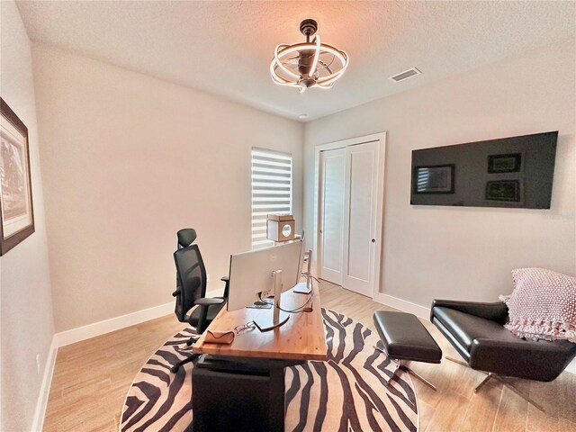 home office featuring light hardwood / wood-style flooring and a textured ceiling