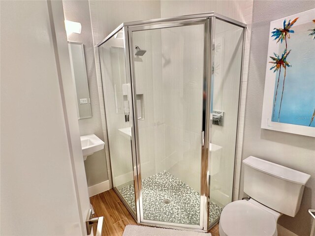 bathroom with wood-type flooring, an enclosed shower, and toilet