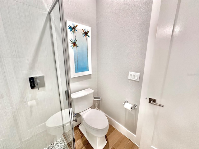 bathroom featuring a shower with door and toilet