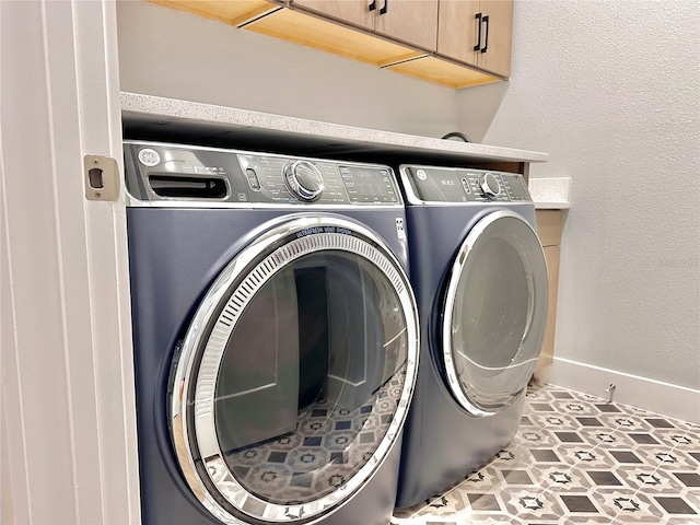 laundry area with cabinets, washing machine and dryer, and light tile patterned floors