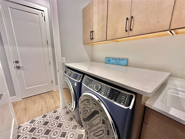 washroom featuring cabinets, washing machine and clothes dryer, and light hardwood / wood-style floors