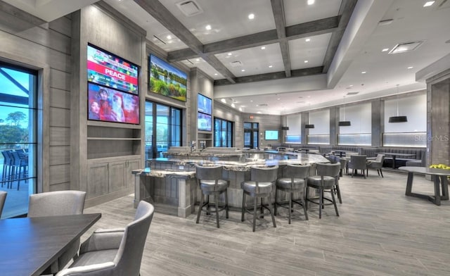 interior space with beam ceiling, coffered ceiling, a wealth of natural light, and light stone counters