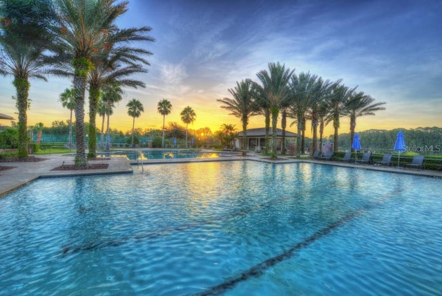 pool at dusk with a patio area