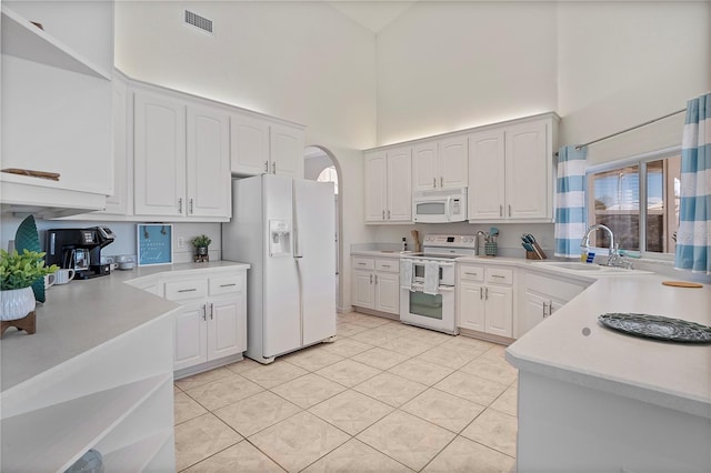 kitchen with light tile patterned flooring, white cabinetry, sink, a high ceiling, and white appliances