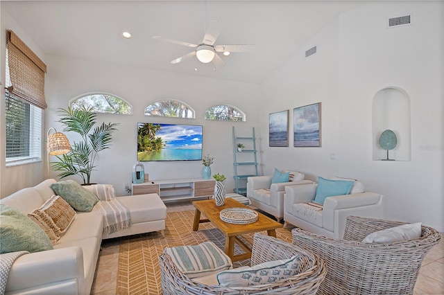 tiled living room with ceiling fan and high vaulted ceiling