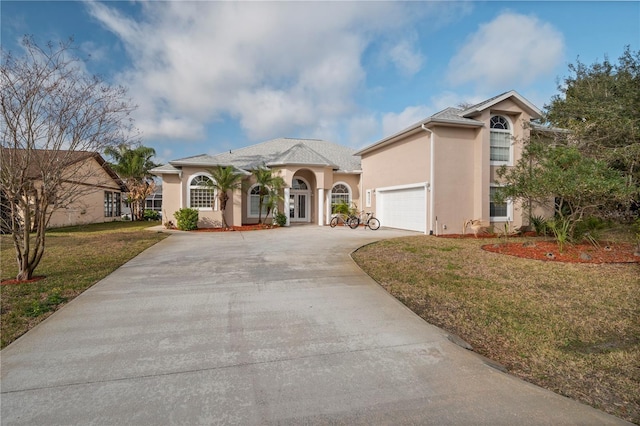 mediterranean / spanish-style home featuring a garage and a front lawn