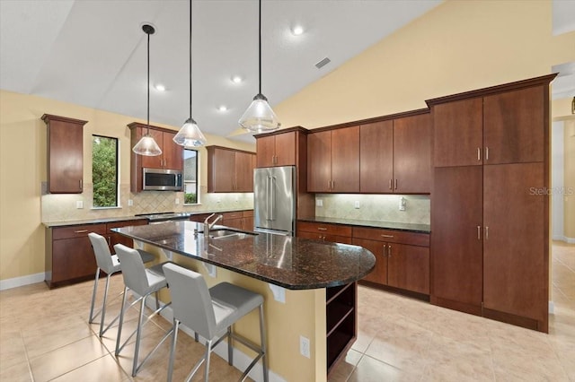 kitchen featuring sink, appliances with stainless steel finishes, a kitchen island with sink, hanging light fixtures, and tasteful backsplash