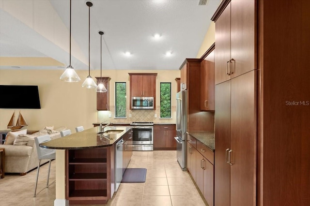 kitchen with sink, a breakfast bar area, backsplash, stainless steel appliances, and decorative light fixtures