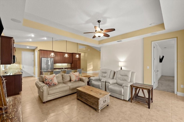 tiled living room with a raised ceiling and ceiling fan