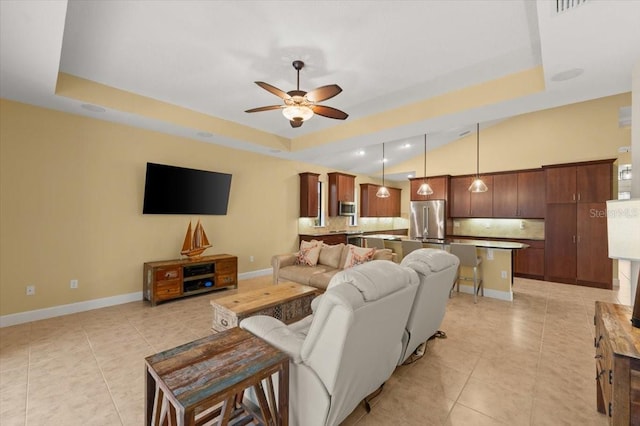 living room with a raised ceiling, light tile patterned floors, and ceiling fan