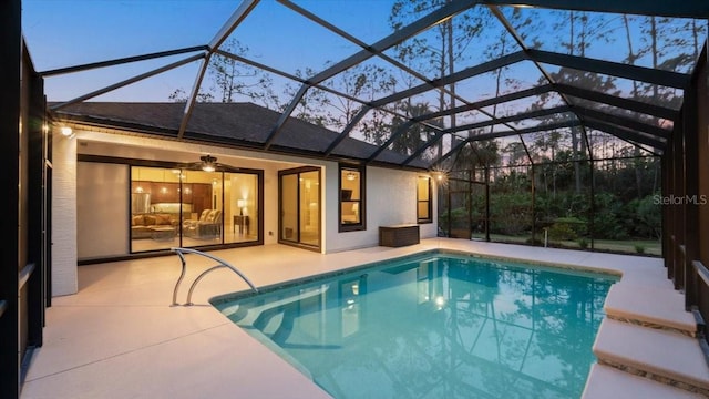 pool at dusk with ceiling fan, a lanai, and a patio