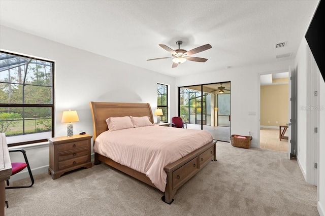 bedroom with ceiling fan, light carpet, and a textured ceiling