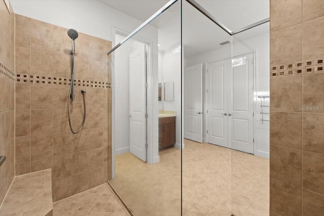 bathroom with vanity, tile patterned flooring, tile walls, and a tile shower