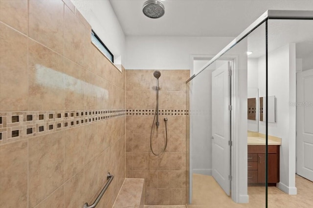 bathroom featuring vanity, a tile shower, and tile patterned floors