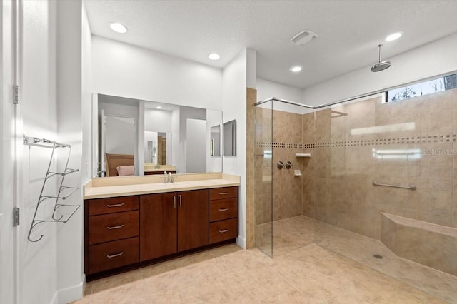 bathroom featuring tiled shower and vanity