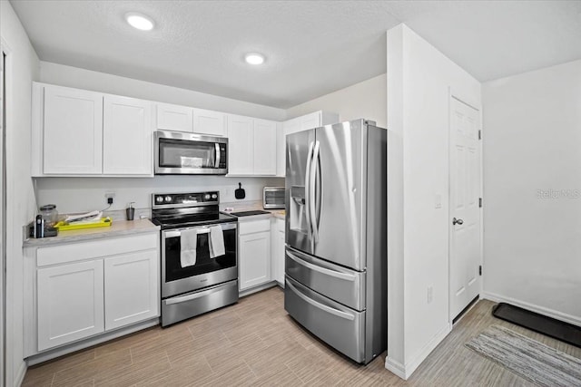 kitchen featuring white cabinetry, stainless steel appliances, and a textured ceiling