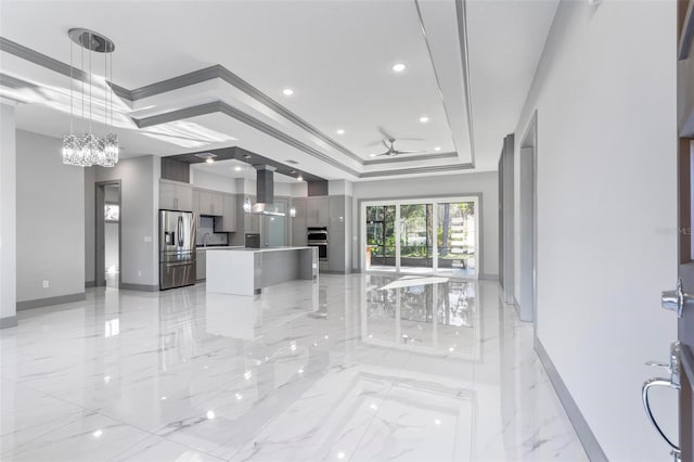 kitchen with gray cabinetry, stainless steel appliances, a center island, island exhaust hood, and a raised ceiling