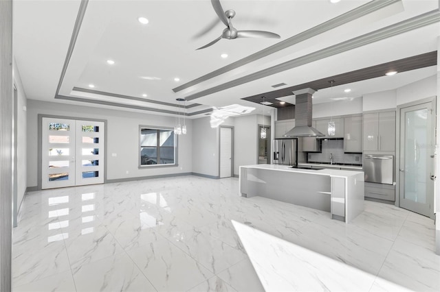 kitchen with a large island, stainless steel fridge, island exhaust hood, decorative light fixtures, and a raised ceiling