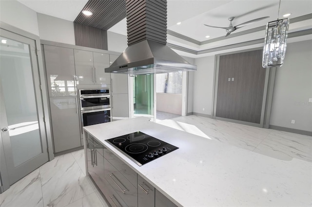 kitchen with island range hood, decorative light fixtures, stainless steel double oven, black electric stovetop, and light stone countertops