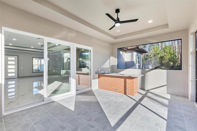 sunroom / solarium with ceiling fan and a tray ceiling