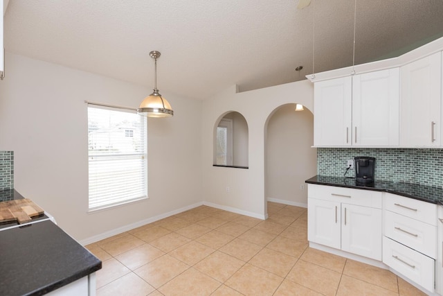 kitchen with pendant lighting, backsplash, light tile patterned floors, and white cabinets